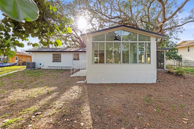 rear view of property featuring a sunroom and central AC