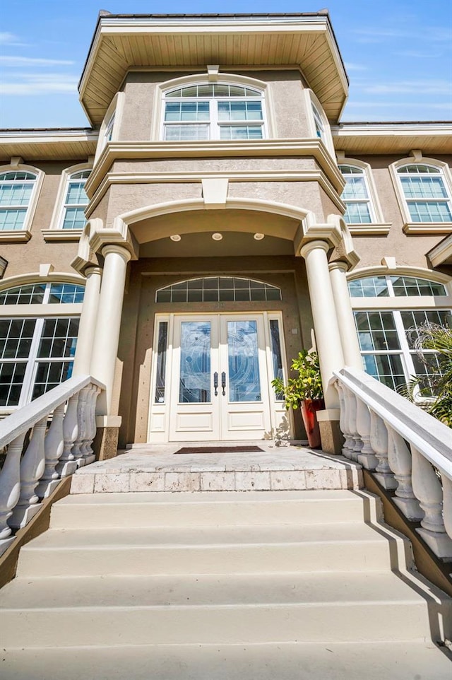 119 8th St E, Tierra Verde, FL 33715 - doorway to property featuring french doors, a porch, and stucco siding