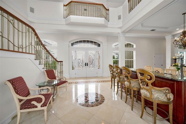 119 8th St E, Tierra Verde, FL 33715 - entrance foyer with a high ceiling, light tile patterned floors, french doors, a chandelier, and decorative columns