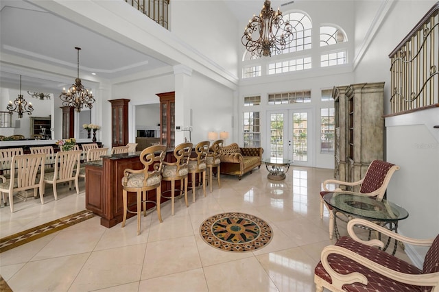 interior space with french doors, a towering ceiling, ornate columns, and light tile patterned flooring