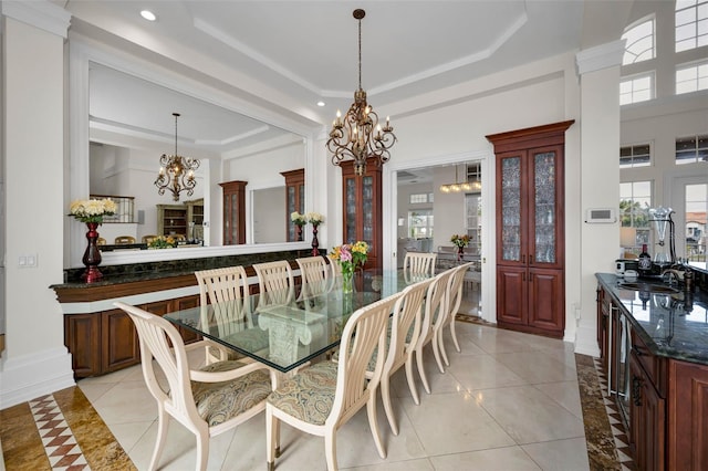 tiled dining space with a chandelier, decorative columns, and sink