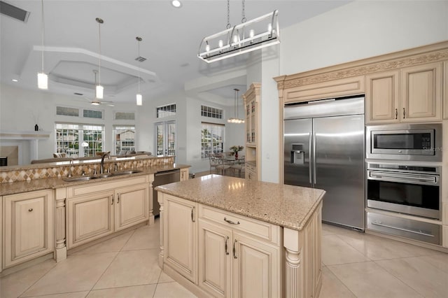 119 8th St E, Tierra Verde, FL 33715 - kitchen featuring built in appliances, cream cabinets, a center island, a ceiling fan, and light tile patterned flooring