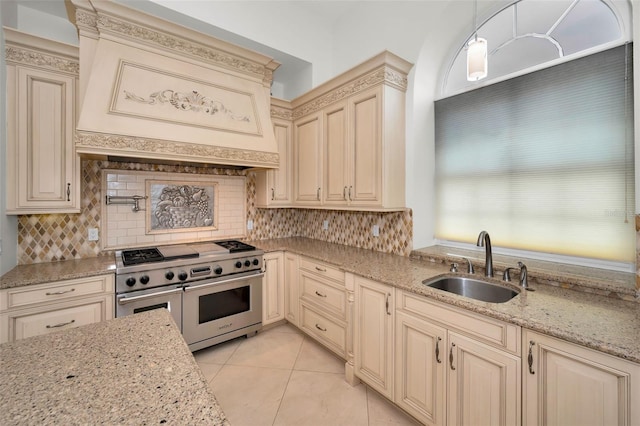 kitchen featuring light stone counters, pendant lighting, double oven range, and sink