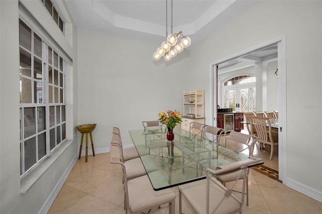 tiled dining room with wine cooler, a raised ceiling, and a notable chandelier