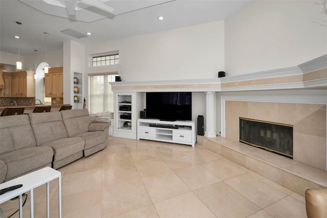 living room with sink, light tile patterned floors, a towering ceiling, and a premium fireplace