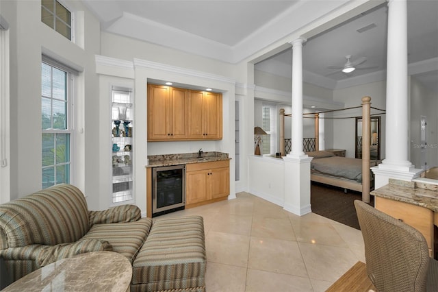 119 8th St E, Tierra Verde, FL 33715 - living room featuring wine cooler, decorative columns, bar with sink, a ceiling fan, and light tile patterned floors