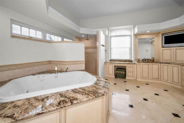 bathroom featuring tile patterned flooring, vanity, and tiled bath