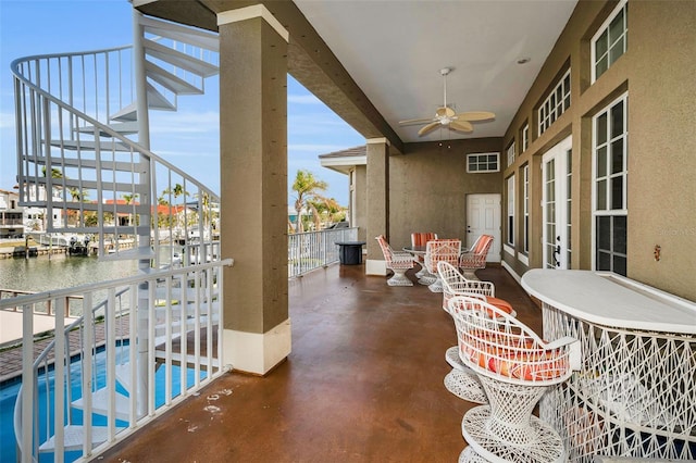 balcony with a water view, ceiling fan, and a patio area