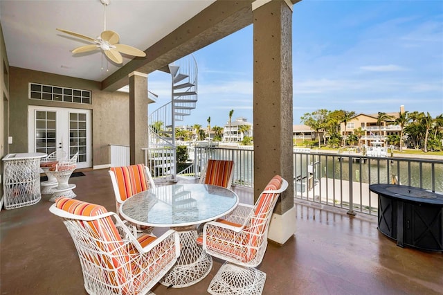 balcony with ceiling fan, french doors, and a water view