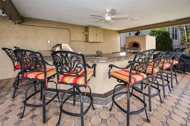 view of patio / terrace featuring exterior bar, exterior fireplace, and ceiling fan