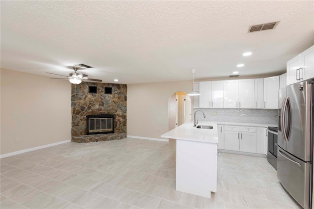 kitchen featuring white cabinetry, sink, ceiling fan, stainless steel appliances, and a fireplace