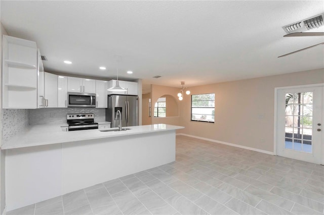 kitchen with kitchen peninsula, decorative light fixtures, stainless steel appliances, and sink