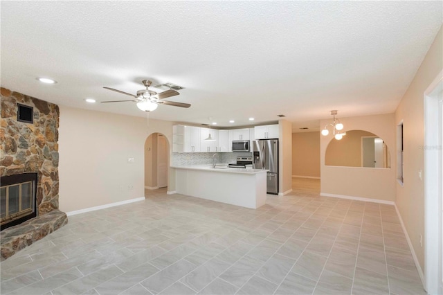 unfurnished living room with a textured ceiling, ceiling fan, a fireplace, and sink