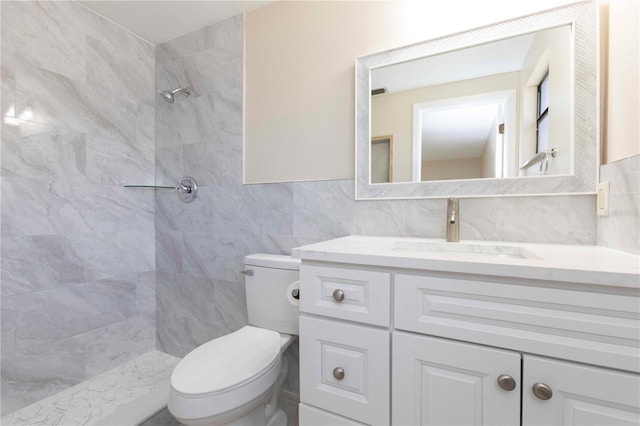 bathroom featuring a tile shower, vanity, toilet, and tile walls