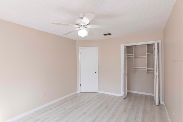 unfurnished bedroom featuring ceiling fan, light wood-type flooring, a textured ceiling, and a closet