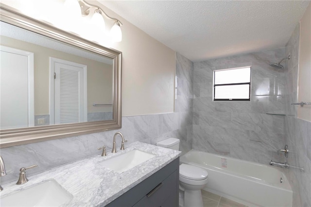 full bathroom with vanity, tiled shower / bath combo, a textured ceiling, and toilet