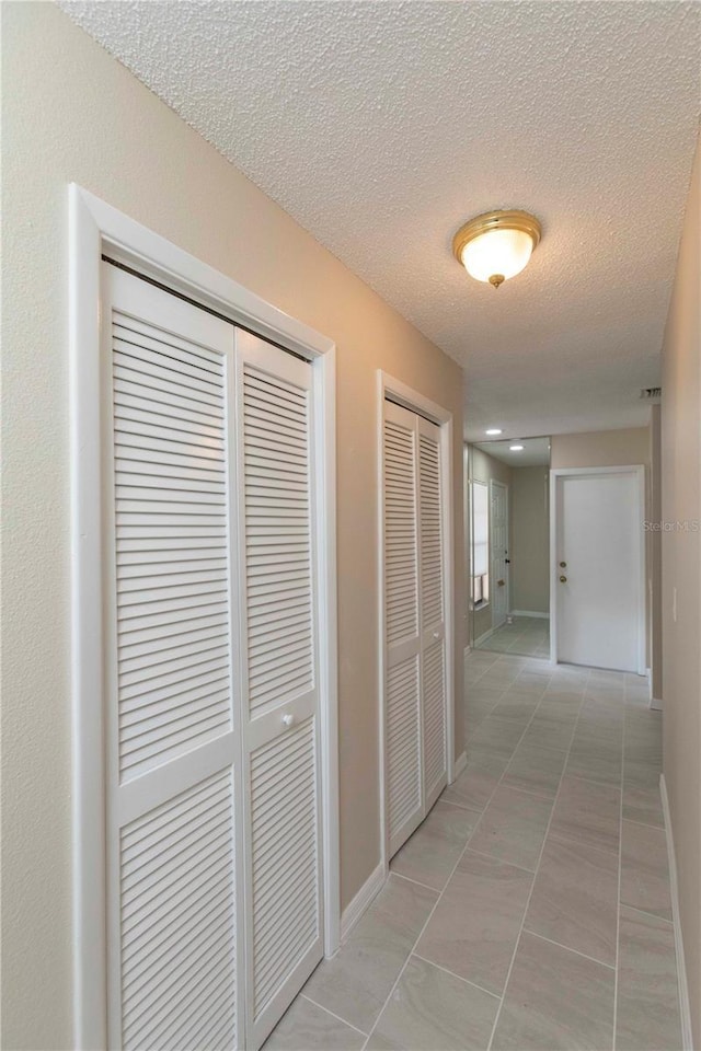 hall featuring light tile patterned floors and a textured ceiling