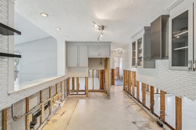 kitchen with gray cabinetry, lofted ceiling, and a textured ceiling