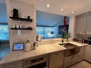 kitchen with tasteful backsplash, gray cabinetry, light stone counters, and a healthy amount of sunlight