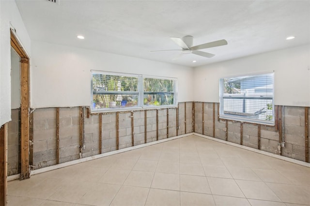 unfurnished room featuring tile walls, plenty of natural light, and ceiling fan