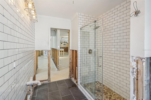 bathroom with tile patterned floors, crown molding, tile walls, a notable chandelier, and a shower with shower door