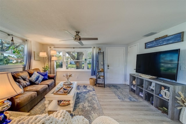 living room with ceiling fan, light hardwood / wood-style floors, and a textured ceiling