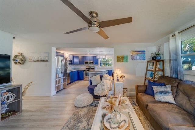 living room featuring a textured ceiling, light hardwood / wood-style floors, and ceiling fan