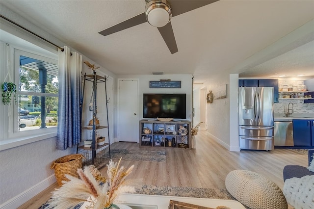 living room with a textured ceiling, light hardwood / wood-style floors, and ceiling fan