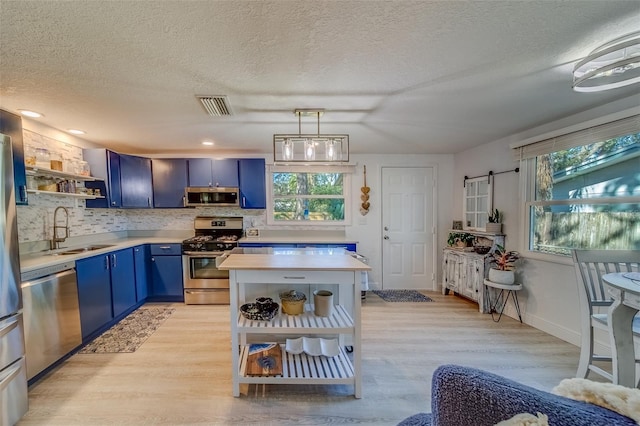 kitchen featuring stainless steel appliances, blue cabinets, a wealth of natural light, and sink