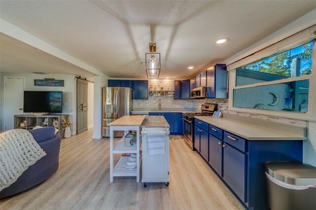 kitchen featuring tasteful backsplash, a textured ceiling, stainless steel appliances, blue cabinetry, and light hardwood / wood-style floors