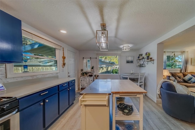 kitchen featuring a textured ceiling, light hardwood / wood-style floors, range, and blue cabinetry