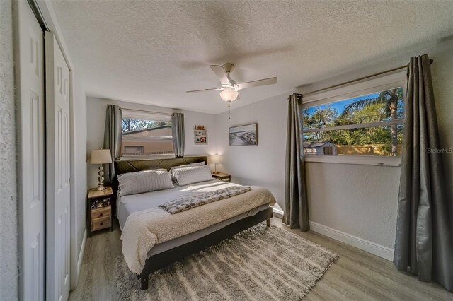 bedroom featuring ceiling fan, light wood-type flooring, and a textured ceiling