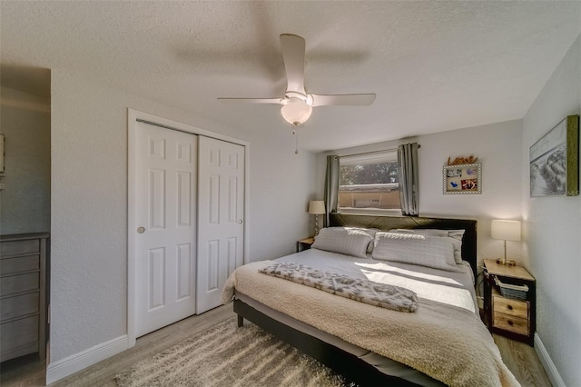 bedroom with a textured ceiling, hardwood / wood-style flooring, a closet, and ceiling fan