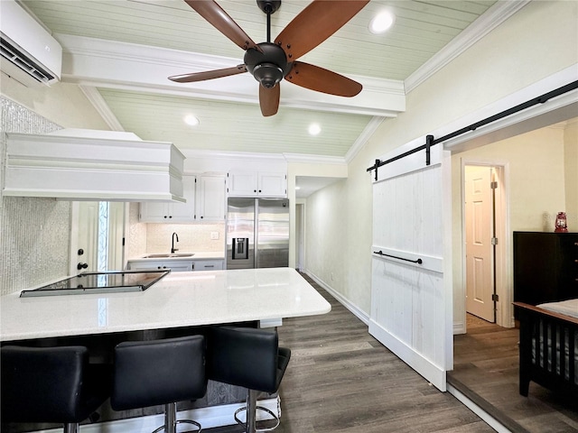 kitchen featuring dark wood-type flooring, a barn door, white cabinets, stainless steel fridge with ice dispenser, and a breakfast bar area