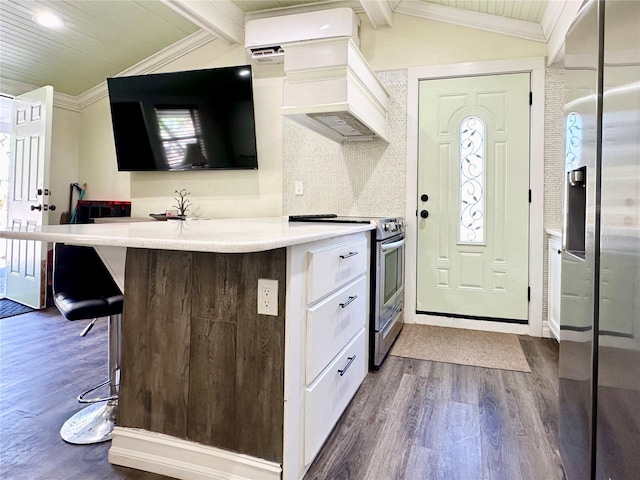 kitchen featuring dark wood-type flooring, lofted ceiling with beams, crown molding, a breakfast bar, and appliances with stainless steel finishes