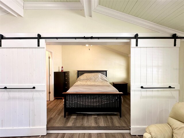 bedroom with hardwood / wood-style floors, lofted ceiling with beams, and a barn door