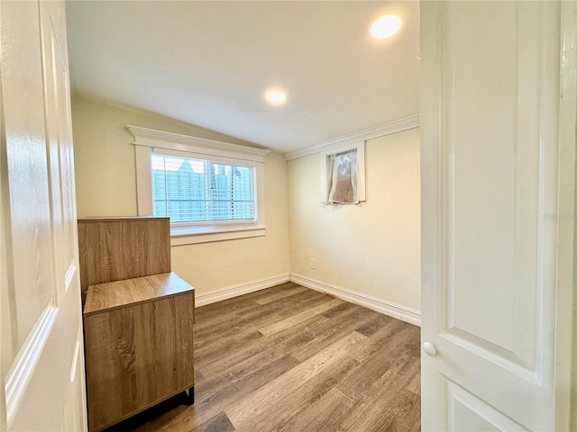 unfurnished room featuring hardwood / wood-style floors, crown molding, and lofted ceiling