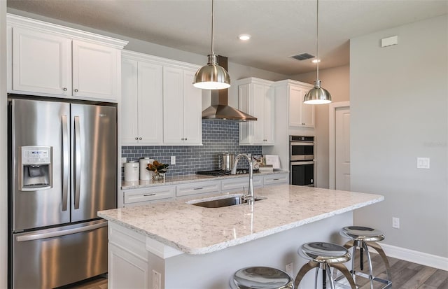 kitchen with appliances with stainless steel finishes, white cabinetry, and an island with sink