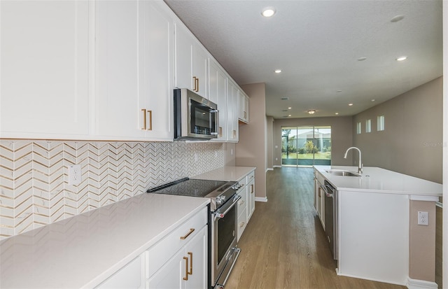 kitchen featuring white cabinetry, an island with sink, light hardwood / wood-style flooring, sink, and appliances with stainless steel finishes