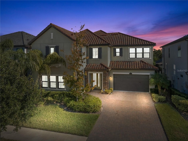 mediterranean / spanish house with a garage and a lawn