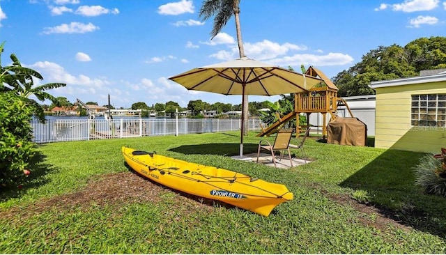 view of property's community with a yard, a playground, and a water view