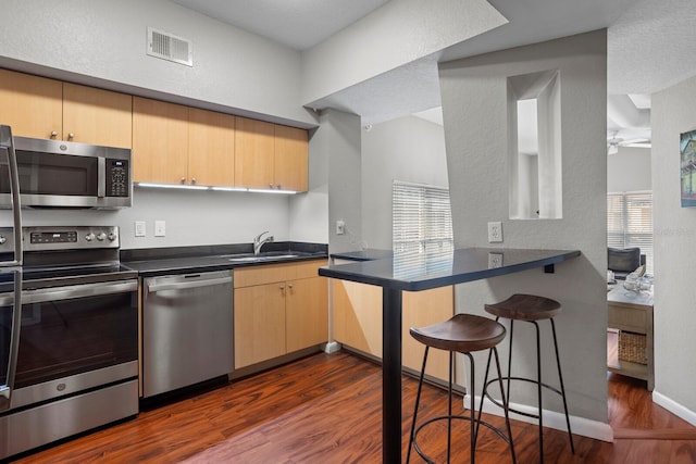 kitchen featuring light brown cabinets, dark wood-type flooring, sink, appliances with stainless steel finishes, and kitchen peninsula