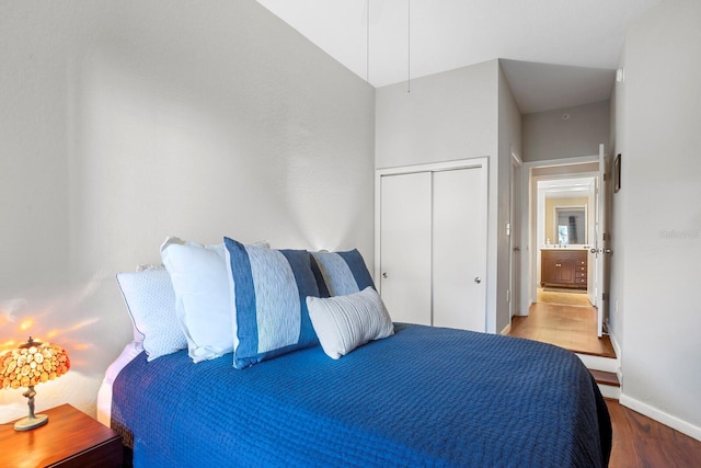 bedroom featuring a closet, wood-type flooring, and vaulted ceiling