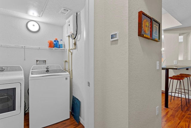 clothes washing area featuring washer and dryer, a textured ceiling, and wood-type flooring