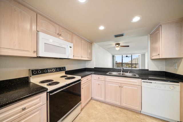 kitchen featuring light brown cabinetry, white appliances, dark stone counters, and sink