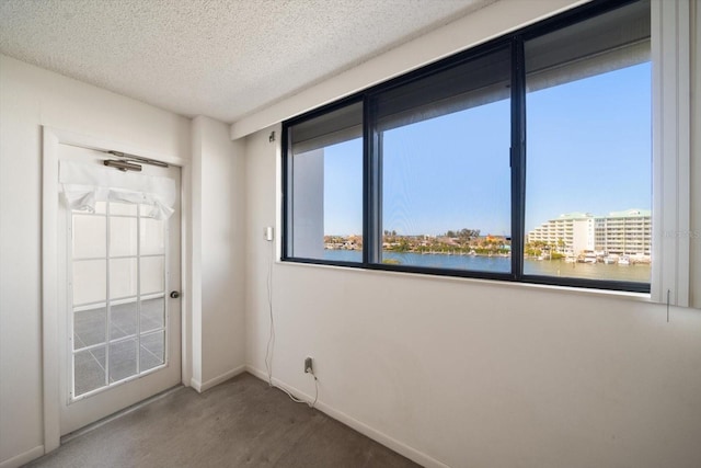 carpeted spare room featuring a textured ceiling and a water view