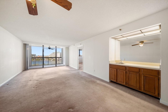 unfurnished living room with sink, light colored carpet, and a textured ceiling