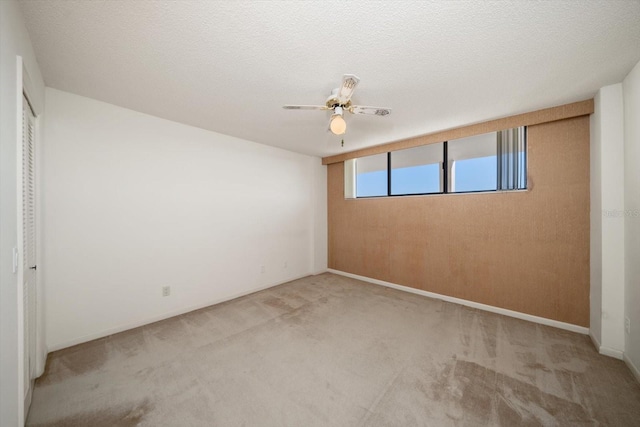 unfurnished bedroom with light carpet, a textured ceiling, and ceiling fan