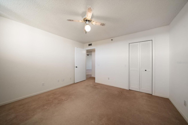 unfurnished bedroom featuring carpet flooring, a textured ceiling, a closet, and ceiling fan