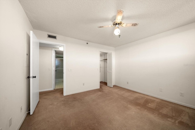 unfurnished bedroom with carpet flooring, ceiling fan, a textured ceiling, and a closet